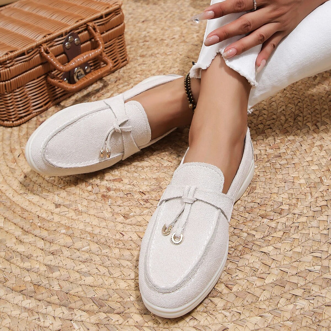 Vrouw draagt witte leren loafers op rieten mat, casual lente-herfst schoenen, hoge kwaliteit, slip-on design, stijlvolle damesmode.